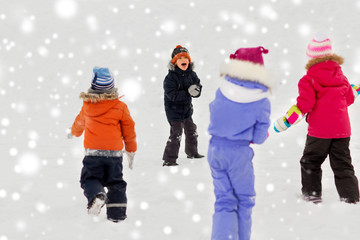 childhood, leisure and season concept - group of happy little kids playing outdoors in winter