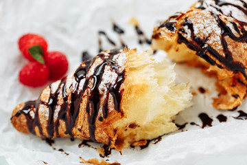 Tasty croissant with cream and topping on plate. Close-up shot with tasty fresh texture of liquid chocolate