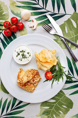 Rolled Delicious Crepes stuffed with chicken and mushrooms on the white plate serving with sour cream. Pancake is a flat cake, often thin and round, prepared from a starch based batter that may
