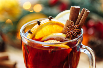 Christmas mulled red wine with spices and fruits on a wooden rustic table. Traditional hot drink at...