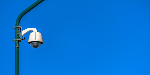 Fototapeta na wymiar Security camera on a pole against blue background