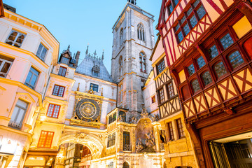 Obraz premium Street view with illuminated buildings and famous clock tower during the twilight in the old town of Rouen city in France