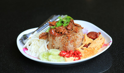 Fried rice mixed Shrimp paste with pork and fried egg in plate on black table. Thai food (Kao Cluk Ka Pi).