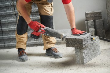 bricklayer cutting ceramsite concrete blockswith saw at walling