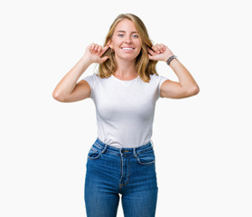 Obraz na płótnie Canvas Beautiful young woman wearing casual white t-shirt over isolated background Smiling pulling ears with fingers, funny gesture. Audition problem