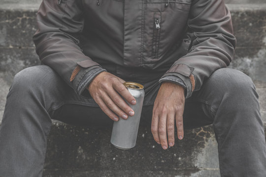 Young man's hand holding metallic can. Beer drinking. Suffering from life difficulties or psychological problems. Depressive atmosphere. Dark, gloomy thoughts. Social isolation. Front view.