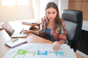 businesswoman model using laptop computer while working on company summary report with graph