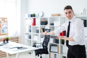 Fototapeta premium A young man in the office invites you to sit down at the table.