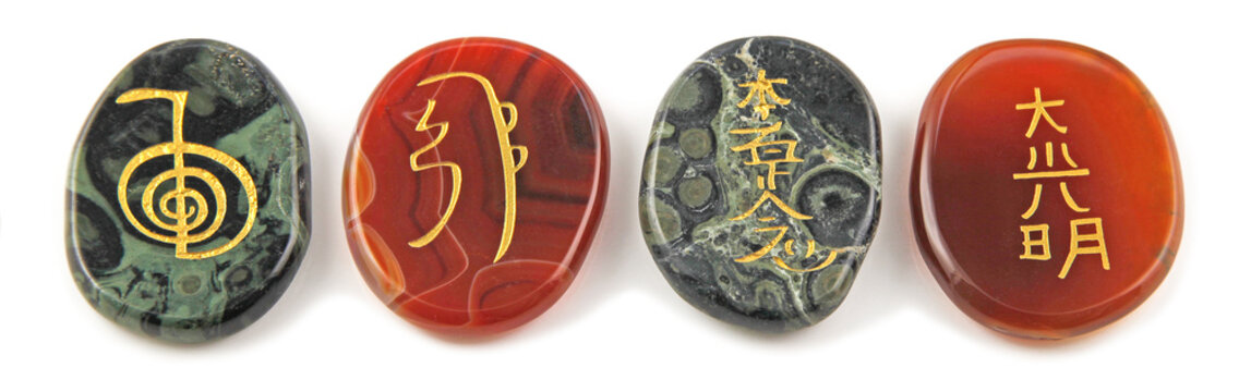The four major Reiki Healing Symbols - etched into palm stones made of Carnelian and Kambaba Jasper placed in a neat row against a white background
