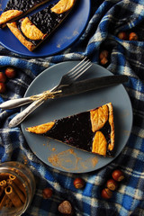 Christmas cake with blueberries on the blanket. Sliced pieces on plates. Hazelnut. Cinnamon sticks. Blue background. Flat lay
