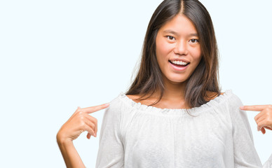 Young asian woman over isolated background looking confident with smile on face, pointing oneself...