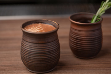 Cup of coffee on wooden table in restaurant. Hot beverage on coffee shop. Clay cup in ethno style.