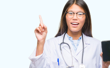 Young asian doctor woman holding smartphone over isolated background surprised with an idea or question pointing finger with happy face, number one