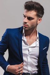 Obraz premium fashion man holding his coat's collar and looks to side