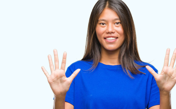 Young asian woman over isolated background showing and pointing up with fingers number ten while smiling confident and happy.