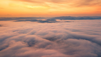 Fototapeta na wymiar Foggy dawn in mountains. Sea of fog between mountain peaks