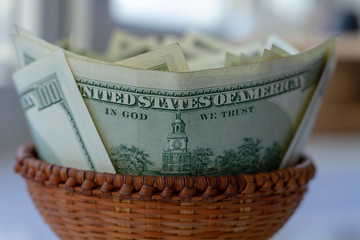 Full wicker basket with money. A lot of cash. Lots of green cash in a wicker basket for small expenses. Cash American dollars closeup with blur and bokeh effect.
