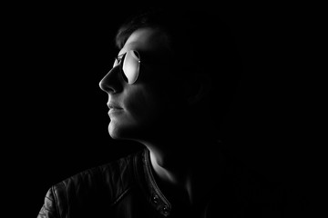 Young man's portrait. Close-up young man in a black leather jacket and sunglasses. Black and white image