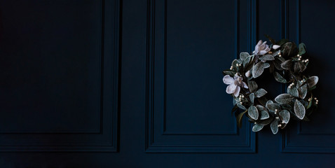 Advent wreath with white flowers and christmas decoration on rustic dark blue wall, panoramic format with copy space, selected focus, narrow depth of field
