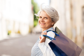 sale, consumerism and people concept - senior woman with shopping bags in city