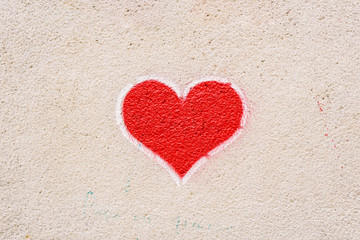Red heart painted on a wall, message of love.