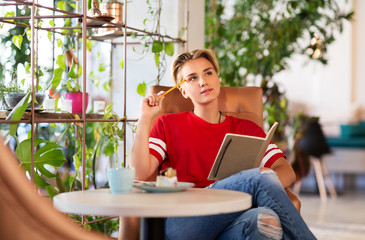 people, leisure and inspiration concept - woman or teenage girl with notebook at coffee shop or cafe