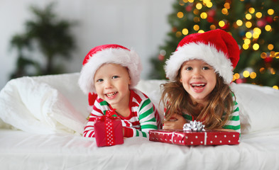 happy children in pajamas with gifts on christmas morning near   tree.
