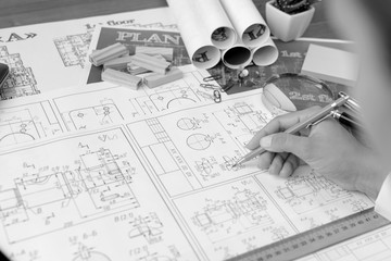A girl (architect, student, businesswoman) works (draws, counts) at a table with business accessories (laptop, smartphone, pens, magnifier), accessories for drawing (plans, rulers) and training