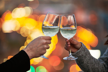 Male and female hands with glasses of wine over night city light