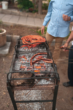 Group of farmers preparing red sausages in a barbecue at sunset, Lorca, Spain