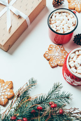 top view of cups of hot chocolate with marshmallows, cookies and christmas present on white tabletop, christmas breakfast concept