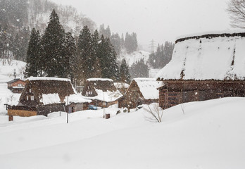 Thatched roof houses in mountains during winter snowstorm