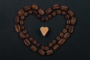 Roasted coffee beans placed in a shape of heart on black background