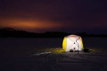 Beautiful Landscape Of Winter Fishing At Night. Yellow Fishing Tent On Ice Under Colorful Sky At Night Winter.