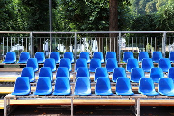 Rows of cobalt blue plastic chairs. Empty tribunes seats in summer german town. Outdoor image.