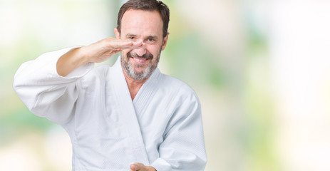 Handsome middle age senior man wearing kimono uniform over isolated background gesturing with hands showing big and large size sign, measure symbol. Smiling looking at the camera. Measuring concept.