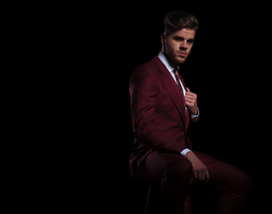 elegant man sitting and holding his collar