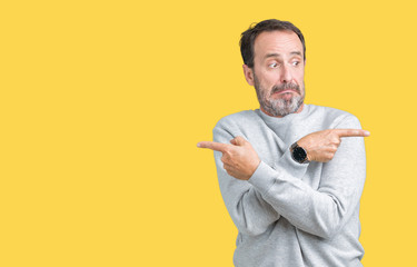 Handsome middle age senior man wearing a sweatshirt over isolated background Pointing to both sides with fingers, different direction disagree
