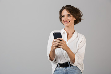 Happy young business woman posing using mobile phone chatting.