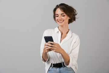 Happy young business woman posing using mobile phone chatting.