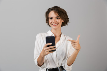 Happy young business woman posing using mobile phone chatting.