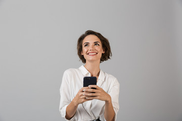 Happy young business woman posing using mobile phone chatting.