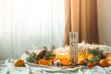 The word HOME and Tangerines in a winter composition, Christmas trees, candles, cones, cotton. Symbol of New Year and Christmas