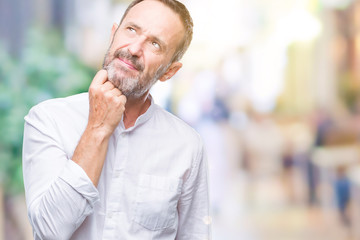 Middle age hoary senior man over isolated background with hand on chin thinking about question, pensive expression. Smiling with thoughtful face. Doubt concept.