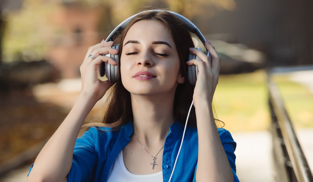 Young woman listening to music with headphones in urban city
