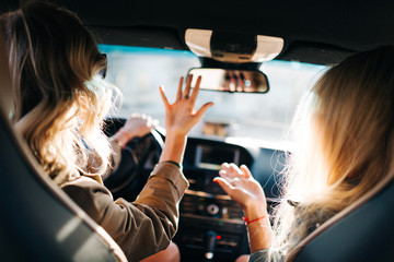 Image of back of two talking women with long hair sitting in car