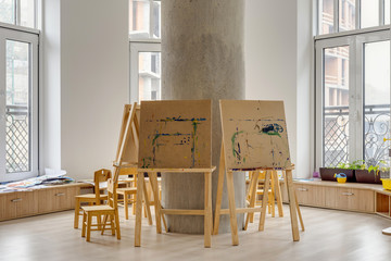 easels and wooden chairs in classroom at modern kindergarten