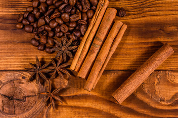 Pile of the coffee beans, star anise and cinnamon sticks on wooden table. Top view