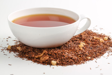 Still life, aromatic dry tea with fruits and petals, close up on with a cup of tea on white background, selective focus