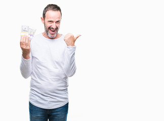 Senior hoary man holding buch of dollars over isolated background pointing and showing with thumb up to the side with happy face smiling